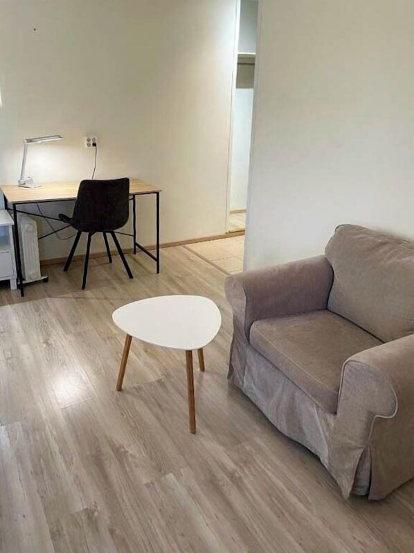 A modern living room with a beige sofa, a small white table, and a wooden floor.