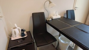 A small, modern room with a black desk, a chair, a lamp, a tissue box, a trash bin, and a coffee maker on a side table. - Budget Double Room - Lapin Satu Hotel (Lapland)