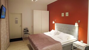 A bedroom with a bed, bedside tables, a wardrobe, a television, and a red accent wall. - Budget Double Room - Lapin Satu Hotel (Lapland)
