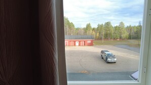 A view through a window of a parking lot with a red building and a truck. - Budget Double Room - Lapin Satu Hotel (Lapland)