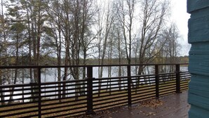 Une terrasse en bois avec une rambarde donnant sur un lac entouré d’arbres.