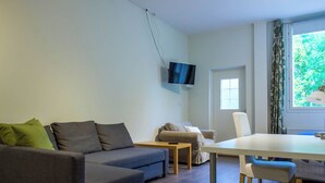 Un salon moderne comprenant un canapé, une table à manger et un téléviseur fixé au mur.