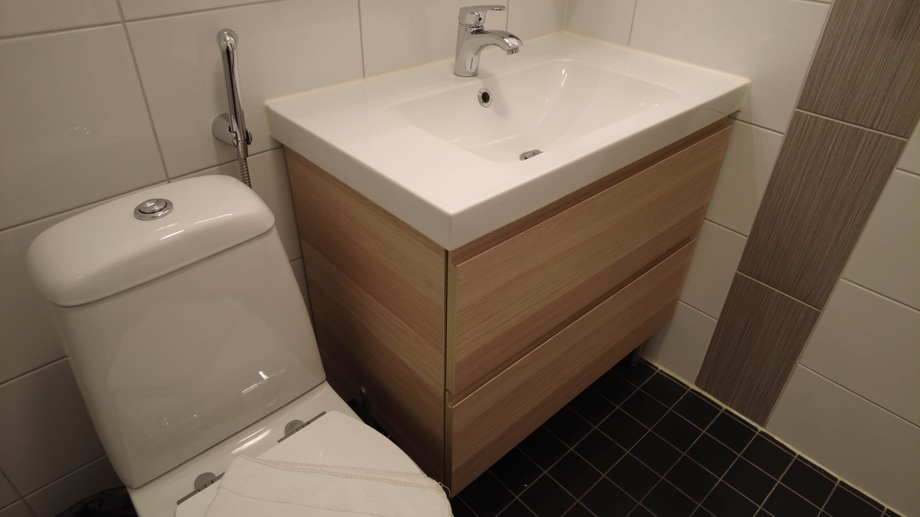 Un baño con inodoro blanco, lavamanos con espejo y tocador de madera.