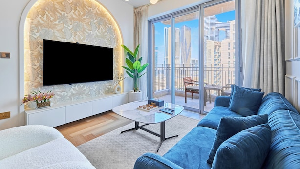 Een moderne woonkamer met een flatscreen televisie, een bank, een salontafel en een balkon met uitzicht op de stad.