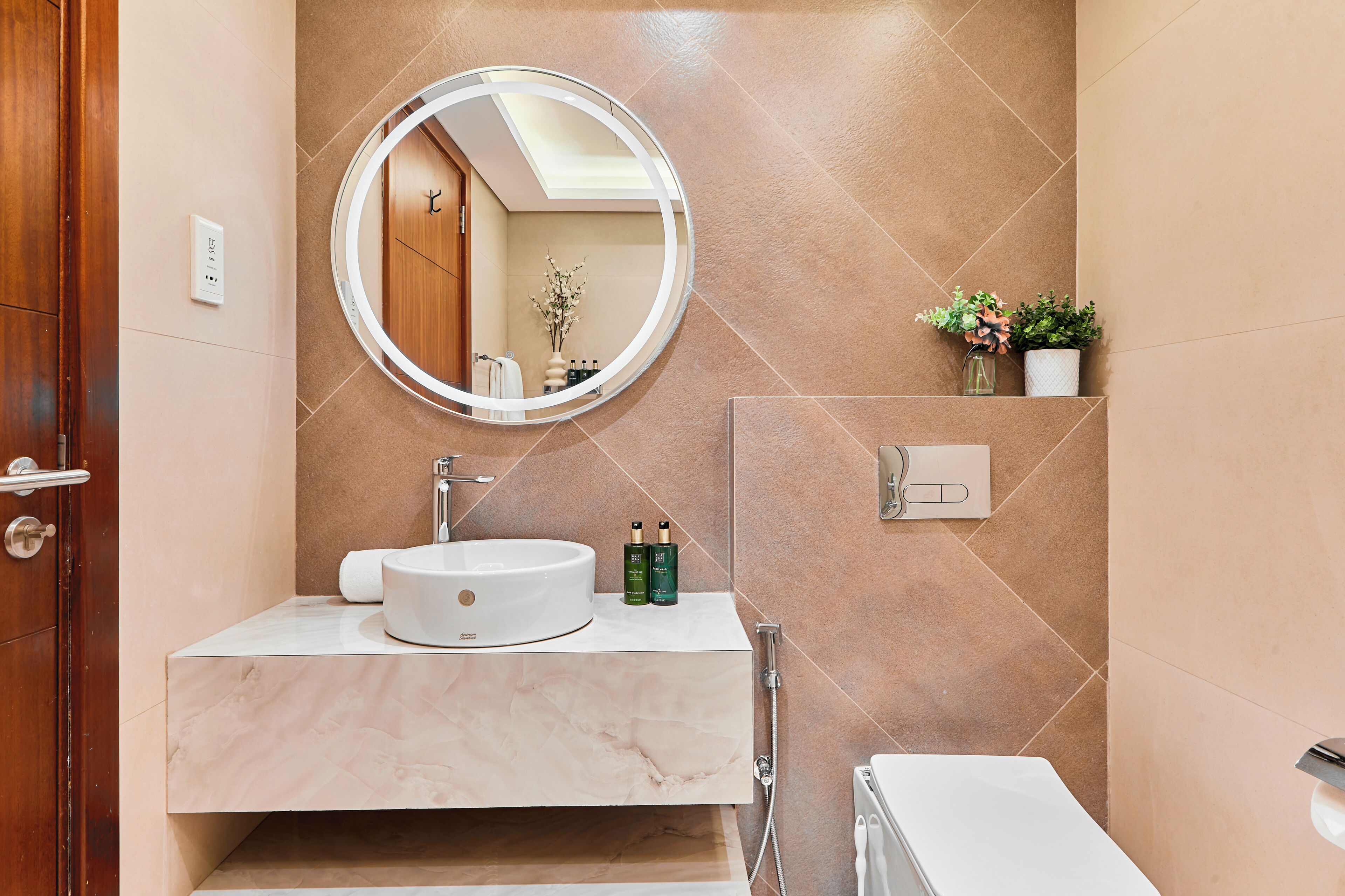 Une salle de bain avec un miroir rond, un lavabo, des toilettes et une douche.