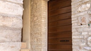 A stone building with a wooden door and a set of stone steps leading to a door. - [Maison Fontebella 56] Assisi Center (Assisi)