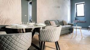 A dining area with a round table set for four, a grey sofa, and a small side table. - [Maison Fontebella 56] Assisi Center (Assisi)