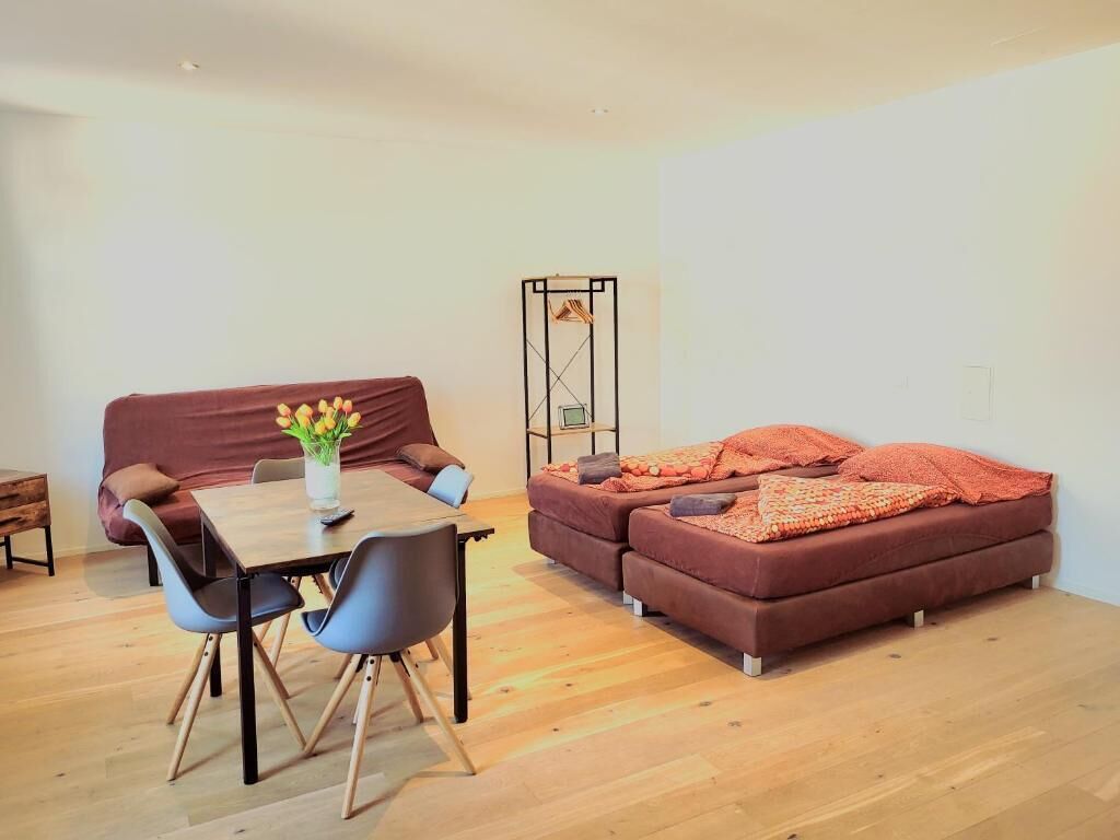 A modern living room with a wooden dining table, two sofas, and a coffee table.