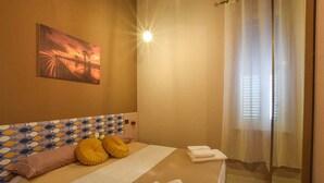Une chambre d’hôtel avec un lit, un tableau au mur et une fenêtre avec des rideaux.