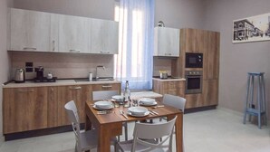 Une cuisine moderne avec des meubles en bois, une table à manger dressée pour deux personnes et un rideau bleu.