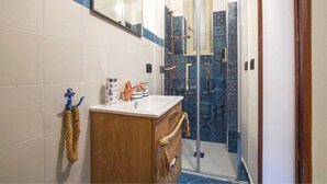Une salle de bain avec un meuble-lavabo en bois, un lavabo blanc et une cabine de douche en verre.