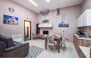 A living room with a sofa, a dining table with chairs, a kitchen area with cabinets and a sink, and a TV on a stand. - Charming 3-bedroom estate with AC, WiFi in Reggio Calabria (Reggio Calabria)