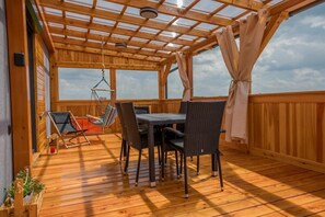 A wooden deck with a table and chairs, a hanging chair, and a view of the sky. - Rajska Polana  (Mieroszów)