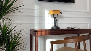 A wooden desk with a lamp, a television mounted on the wall, and a potted plant. - The New Guesthouse Vatican (Rome)