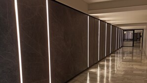 A long, modern hallway with marble flooring and illuminated vertical lines on the walls. - The New Guesthouse Vatican (Rome)