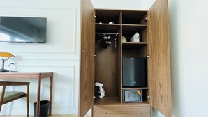 A wooden wardrobe with multiple compartments, a small safe, and a hairdryer inside. - The New Guesthouse Vatican (Rome)