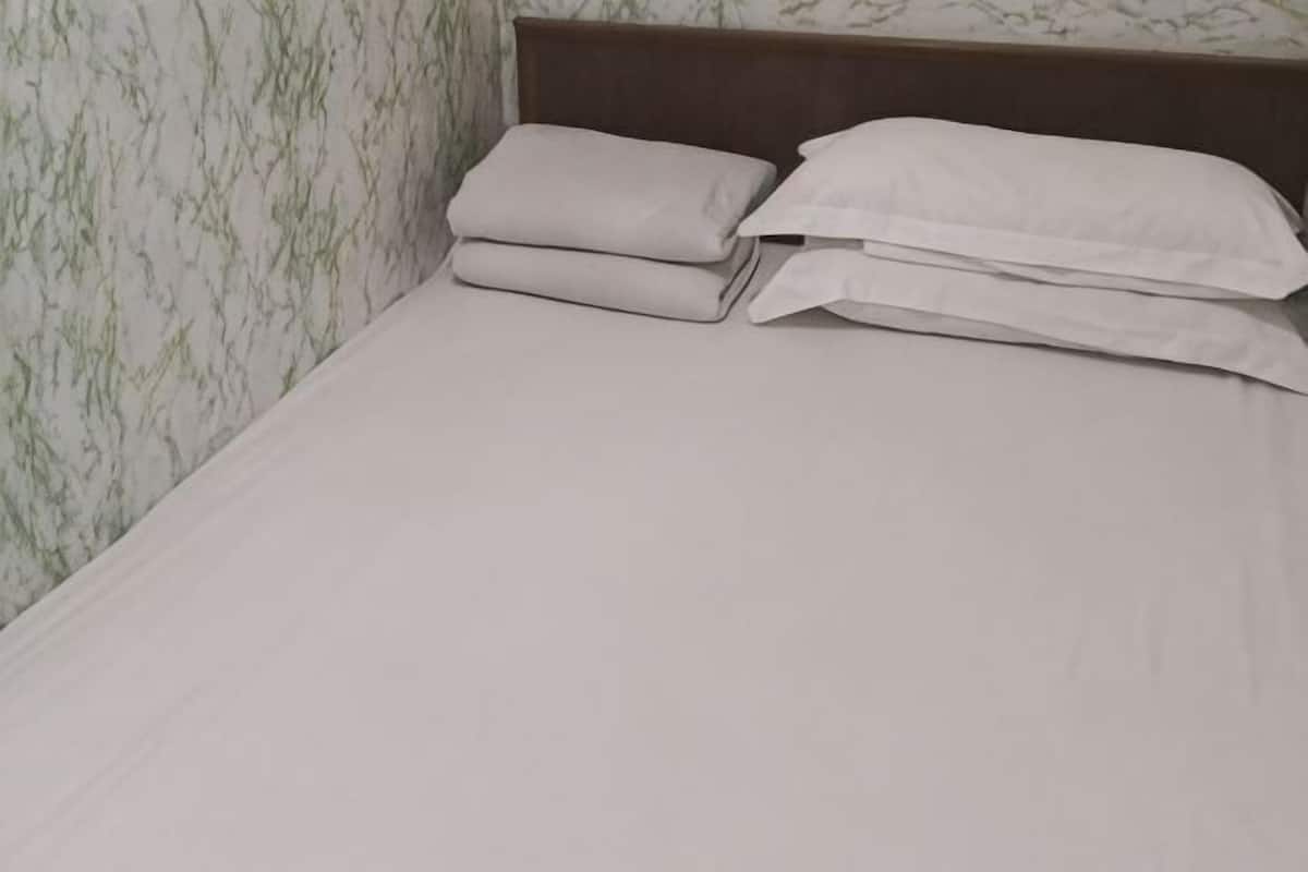A bed with a wooden headboard, white linens, and a marble-patterned wall.