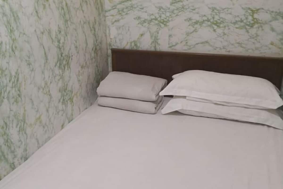 A bed with a wooden headboard, white bedding, and a wall with a green and white pattern.