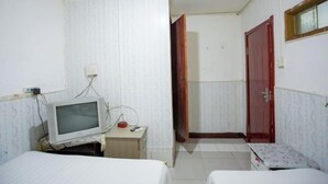 Quarto pequeno e limpo, com uma cama, escrivaninha com televisão e guarda-roupa.