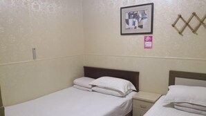 Quarto pequeno com uma cama de solteiro, cabeceira de madeira, mesa de cabeceira e um quadro na parede.