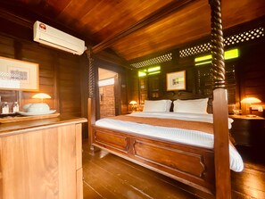 A four-poster bed with a wooden headboard, a bedside table with a lamp, and a picture frame on the wall. - Landmark Cenang (Langkawi)