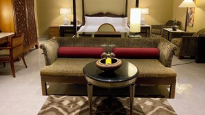 A hotel room with a four-poster bed, a sofa, a small round table with a bowl of fruit, and two bedside lamps. - Landmark Cenang (Langkawi)