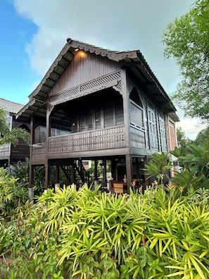 A traditional wooden house with a balcony, surrounded by lush greenery. - Landmark Cenang (Langkawi)