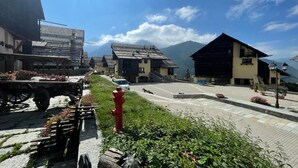 A traditional village street with buildings, a red fire hydrant, and a mountain backdrop. - Grange Hike Ski - 19C Sestriere (Sauze di Cesana)