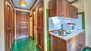 A kitchen with wooden cabinets, a microwave, and a green tiled backsplash. - Grange Hike Ski - 19C Sestriere (Sauze di Cesana)