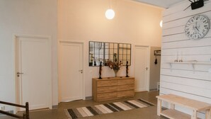 Un couloir avec un banc en bois, une horloge murale et un miroir.