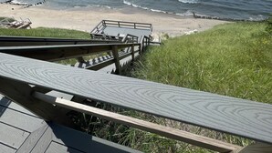 Een houten looppad dat naar een strand leidt, met golven die op de kust breken.