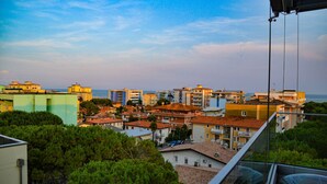 A coastal cityscape with a mix of residential buildings, some with balconies, and a clear view of the sea. - Selene C1-7 in Bibione (San Michele al Tagliamento)