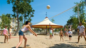 Ein Beachvolleyballspiel mit teilnehmenden Spielern und Zuschauern.