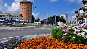 A street view with a round building, a café, and a flower bed. - La Tana Dell Ermellino 3 Ski In Ski Out (Sestriere)