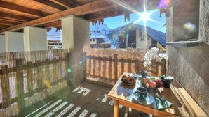 A wooden ceiling with a view of a mountain and a building. A table with dishes and a potted plant is visible. - Grange Hike Ski - Grange Terrace Suite (Sauze di Cesana)