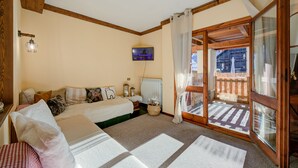 A bedroom with a bed, a television, a window with curtains, and a view of the outside. - Grange Hike Ski - Grange Terrace Suite (Sauze di Cesana)