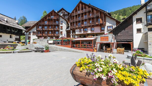 A traditional wooden building with balconies, a central open space with seating, and flower planters. - Grange Hike Ski - Grange Terrace Suite (Sauze di Cesana)