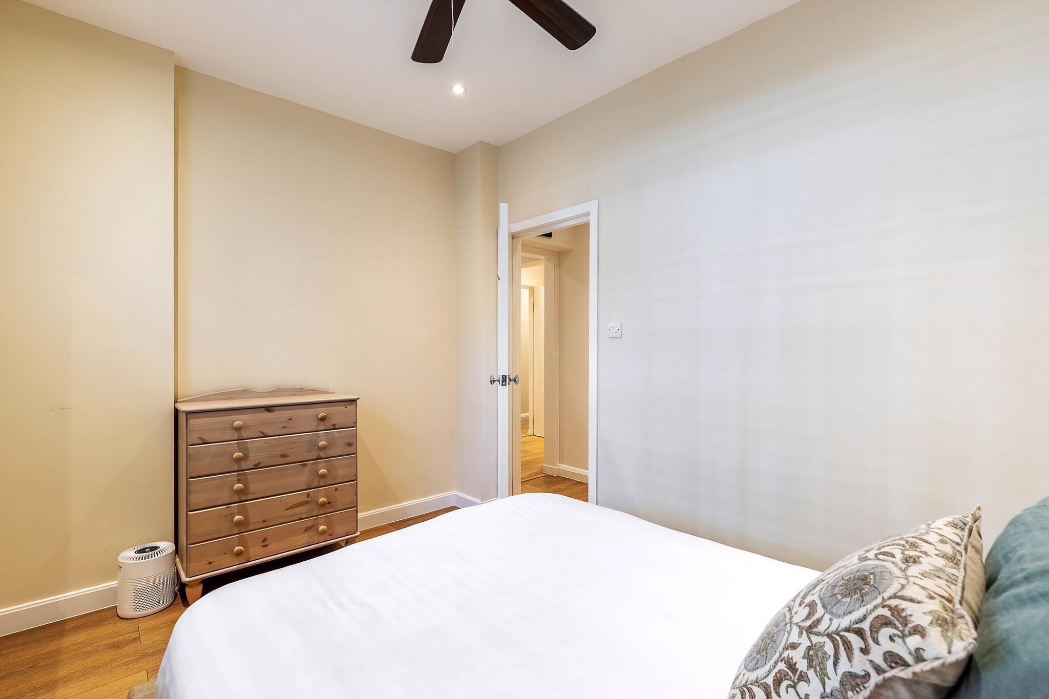 Une chambre à coucher comprenant un lit, une commode et une porte donnant sur une autre pièce.