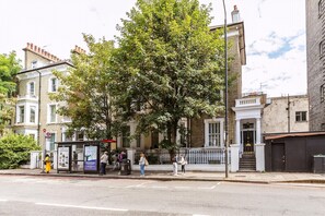 A street scene with a bus stop, pedestrians, and buildings. - Elegant Two Bedroom Flat in Redcliffe Gardens (London)