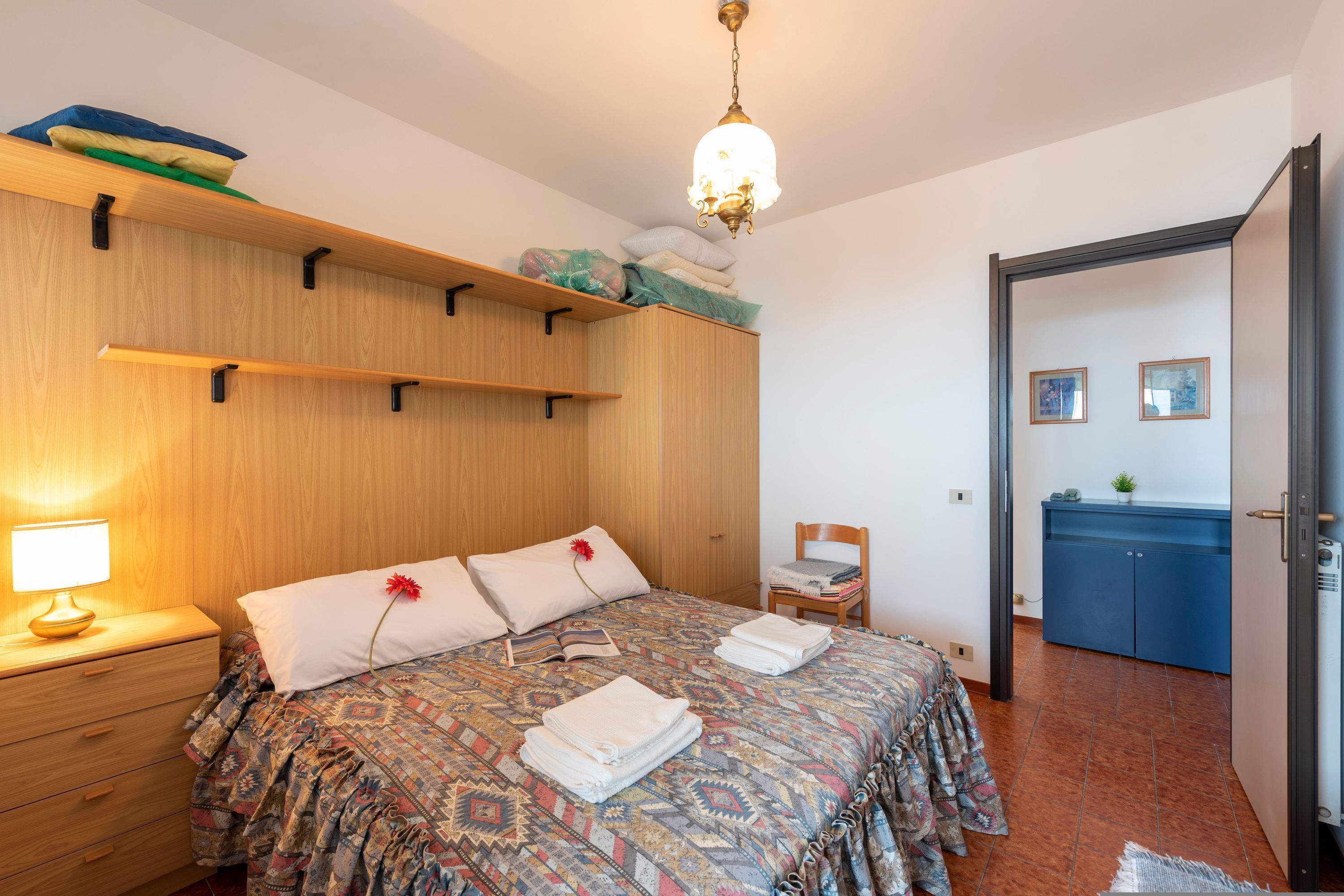 A bedroom with a bed, bedside table, lamp, and a wardrobe.