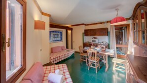 A cozy room with a bed, a dining table with chairs, and a kitchen area.