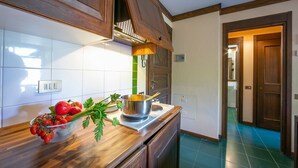 Una cocina con armarios de madera, una estufa y un bol con tomates y perejil en la encimera.