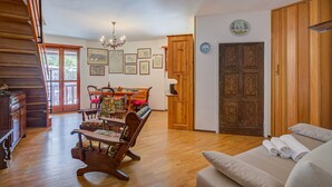 Uma sala de estar ampla com piso de madeira, uma mesa de jantar com cadeiras, um sofá e uma escada.