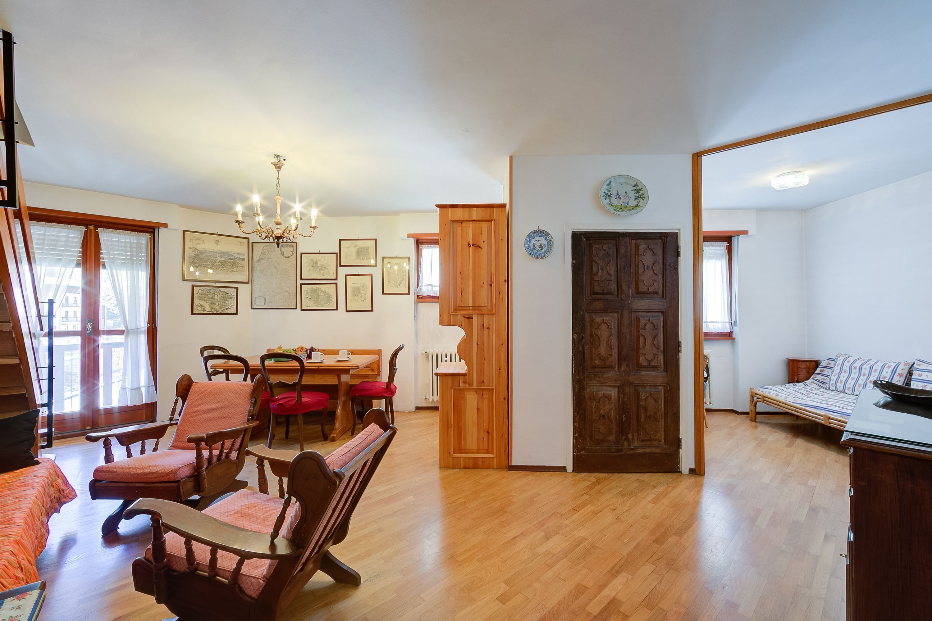 Un espacio habitable amplio con una mesa de comedor, sillas de madera, un sofá y una cama.