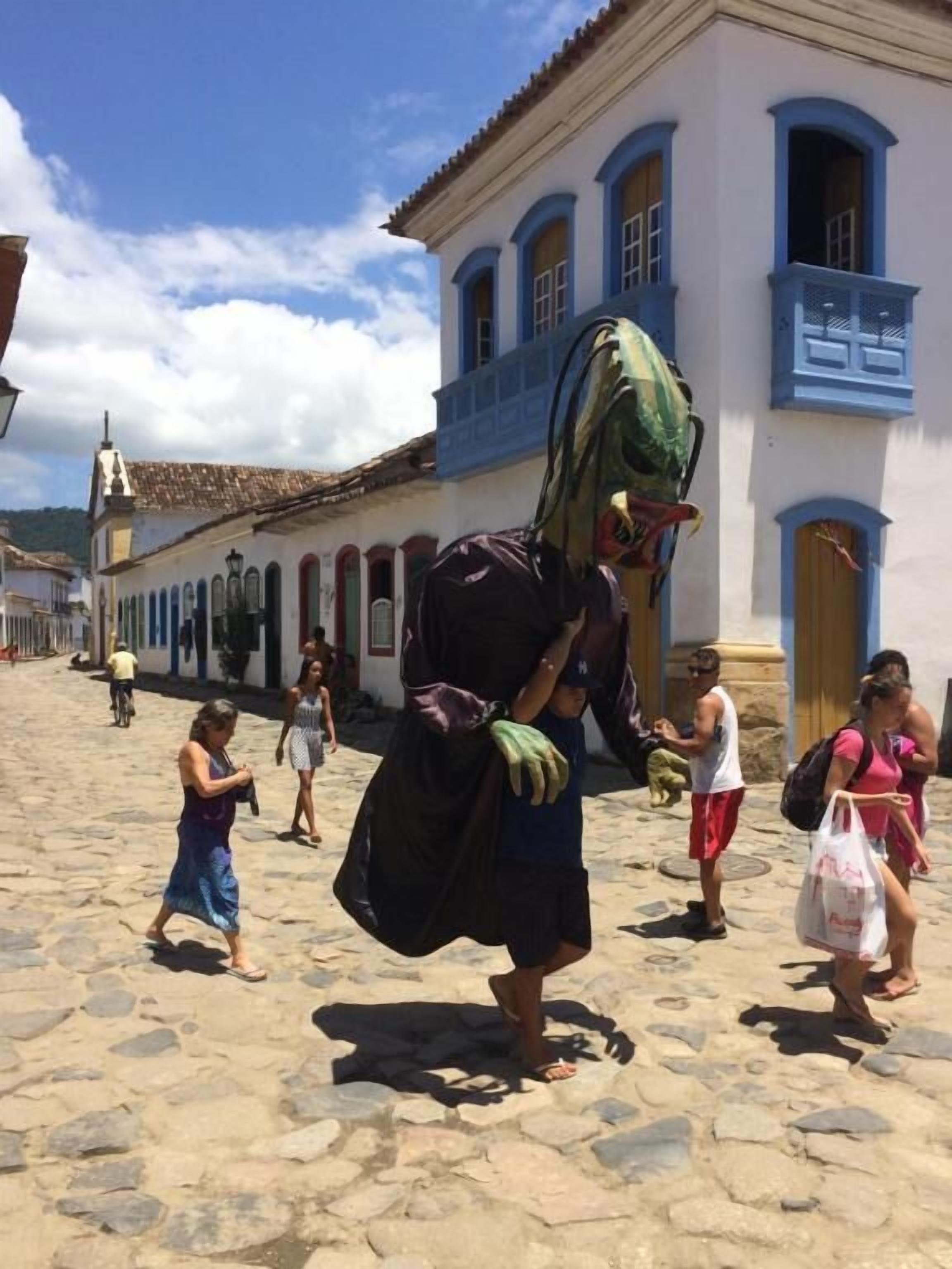 Une rue pavée bordée de bâtiments historiques, une personne en costume et des piétons.
