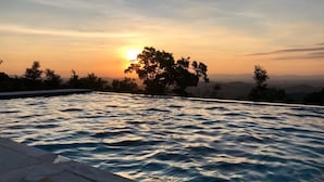 A swimming pool with a sunset view, surrounded by trees and a clear sky. - Magnificat Cottage (Cunha)