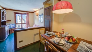 A dining area with a wooden table set for two, a fruit bowl, and a bottle of wine. - Grange Hike Ski - 35C Sestriere (Sauze di Cesana)