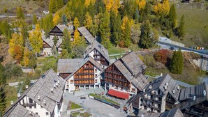A cluster of traditional wooden buildings with steep roofs, likely a historic inn or guesthouse, surrounded by autumn foliage and a small parking area. - Grange Hike Ski - 35C Sestriere (Sauze di Cesana)