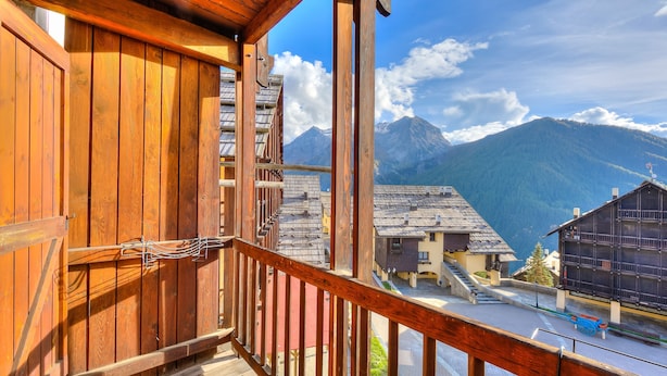 A wooden balcony with a view of a mountain and a village below. - Grange Hike Ski - 35C Sestriere (Sauze di Cesana)