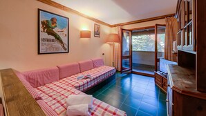 A cozy living room with a checkered sofa, a wooden cabinet, and a large poster on the wall. - Grange Hike Ski - 37C Sestriere (Sauze di Cesana)